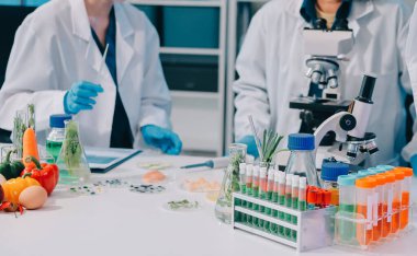 Laboratuvardaki Asyalı bilim adamları mikroskop ve laboratuvar ekipmanları kullanarak gıda araştırmaları yapıyor, gıda bilimi ve biyoteknoloji alanında yenilikler sergiliyorlar.