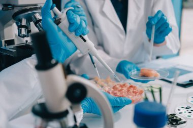 Laboratuvardaki Asyalı bilim adamları mikroskop ve laboratuvar ekipmanları kullanarak gıda araştırmaları yapıyor, gıda bilimi ve biyoteknoloji alanında yenilikler sergiliyorlar.