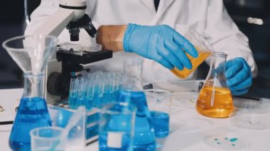 Koruyucu eldivenli bilim adamı laboratuvarda çalışıyor.