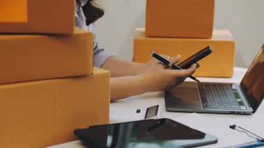 Genç Asyalı işletme sahibi ofiste çalışırken akıllı telefon kullanıyor.