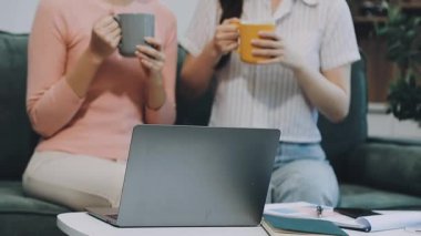 Laptop kullanan ve kahve içen iki genç kadın.