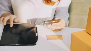 Elinde cep telefonu olan ve dükkanda tablet kullanan genç bir kadın..
