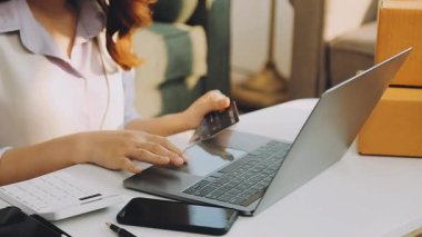 Genç bir kadın online alışveriş için dizüstü bilgisayar kullanıyor..