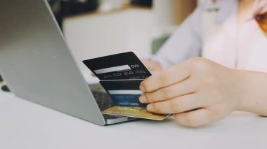 Masada otururken dizüstü bilgisayar ve kredi kartı kullanan kadınların yakın plan görüntüsü