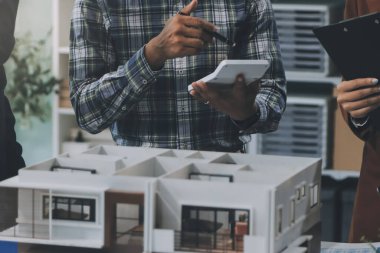 İnşaat, planlama ve mimarlar inşaat, strateji ve endüstriyel işbirliği konularında toplanıyorlar. Mimarlık işçileri kağıt ve modelle bakım projesinden bahsediyorlar.