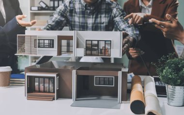 İnşaat, planlama ve mimarlar inşaat, strateji ve endüstriyel işbirliği konularında toplanıyorlar. Mimarlık işçileri kağıt ve modelle bakım projesinden bahsediyorlar.
