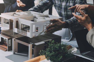 İnşaat, planlama ve mimarlar inşaat, strateji ve endüstriyel işbirliği konularında toplanıyorlar. Mimarlık işçileri kağıt ve modelle bakım projesinden bahsediyorlar.