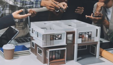 İnşaat, planlama ve mimarlar inşaat, strateji ve endüstriyel işbirliği konularında toplanıyorlar. Mimarlık işçileri kağıt ve modelle bakım projesinden bahsediyorlar.