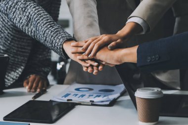 İş dünyası ekibi ellerini birleştiriyor genç iş adamlarının el ele tutuşmalarını yakından izliyorlar. İşlerin başarıya ulaşmasını sağlamak için insanlar takım olarak çalışacaklar.