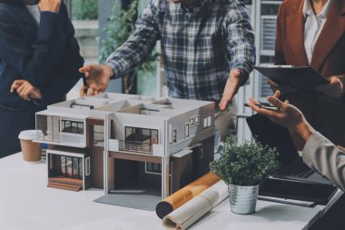 İnşaat, planlama ve mimarlar inşaat, strateji ve endüstriyel işbirliği konularında toplanıyorlar. Mimarlık işçileri kağıt ve modelle bakım projesinden bahsediyorlar.