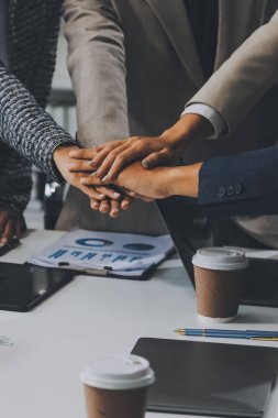 İş dünyası ekibi ellerini birleştiriyor genç iş adamlarının el ele tutuşmalarını yakından izliyorlar. İşlerin başarıya ulaşmasını sağlamak için insanlar takım olarak çalışacaklar.