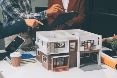 İnşaat, planlama ve mimarlar inşaat, strateji ve endüstriyel işbirliği konularında toplanıyorlar. Mimarlık işçileri kağıt ve modelle bakım projesinden bahsediyorlar.