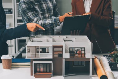 İnşaat, planlama ve mimarlar inşaat, strateji ve endüstriyel işbirliği konularında toplanıyorlar. Mimarlık işçileri kağıt ve modelle bakım projesinden bahsediyorlar.