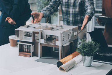 İnşaat, planlama ve mimarlar inşaat, strateji ve endüstriyel işbirliği konularında toplanıyorlar. Mimarlık işçileri kağıt ve modelle bakım projesinden bahsediyorlar.