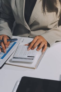 Asyalı iş kadını dizüstü bilgisayar kullanıyor ve ofiste hesap makinesi ile çalışıyor, mali raporu, iş planı yatırımını, mali analiz konseptini analiz etmeyi planlıyor..