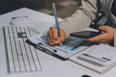Asyalı iş kadını dizüstü bilgisayar kullanıyor ve ofiste hesap makinesi ile çalışıyor, mali raporu, iş planı yatırımını, mali analiz konseptini analiz etmeyi planlıyor..