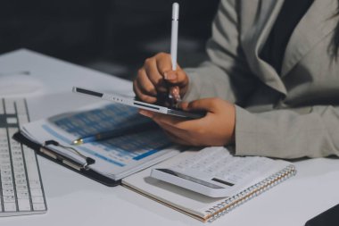 Asyalı iş kadını dizüstü bilgisayar kullanıyor ve ofiste hesap makinesi ile çalışıyor, mali raporu, iş planı yatırımını, mali analiz konseptini analiz etmeyi planlıyor..