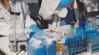 Yakın plan - eldivenli bilim adamı laboratuarda matarayı tutuyor.