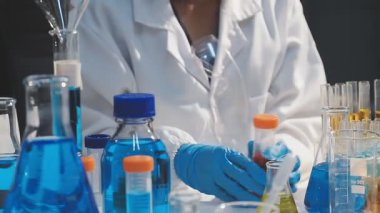 Laboratuvarda deney tüplerini sıvı ve pipetle tutan bilim adamının yakın görüntüsü