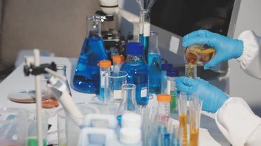 Laboratuvarda deney tüpü olan koruyucu eldivenli ve gözlüklü bilim adamı.