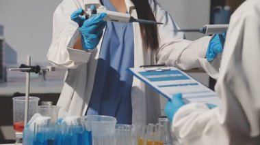 Laboratuvarda sıvı ve sıvı bardakları tutan kadın bir laboratuvar çalışanı.