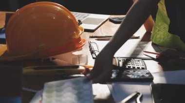 Bilgisayarı ve hesap makinesi olan bir inşaat işçisi.