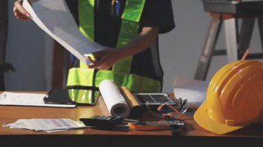 Üniformalı işçi, miğfer, güvenlik yeleği, kask, eldiven ve tablet bilgisayar inşaat alanında çalışıyor..