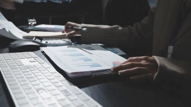 Bilgisayar ekranında dizüstü bilgisayar kullanan ve finansal verileri analiz eden iş adamları.