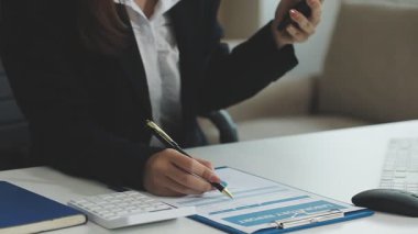 Modern ofiste akıllı telefon kullanan bir iş kadını. Genç bayan ofiste dizüstü bilgisayarla çalışıyor..