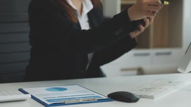 Akıllı telefon kullanan ve ofisteki bilgisayarda çalışan bir iş kadını.