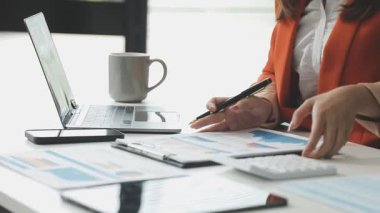 Ofiste belgelerle ve bilgisayarla çalışan bir iş kadını.