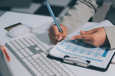 Asyalı iş kadını dizüstü bilgisayar kullanıyor ve ofiste hesap makinesi ile çalışıyor, mali raporu, iş planı yatırımını, mali analiz konseptini analiz etmeyi planlıyor..