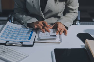 Asyalı iş kadını dizüstü bilgisayar kullanıyor ve ofiste hesap makinesi ile çalışıyor, mali raporu, iş planı yatırımını, mali analiz konseptini analiz etmeyi planlıyor..