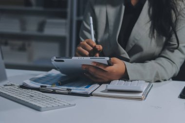 Asyalı iş kadını dizüstü bilgisayar kullanıyor ve ofiste hesap makinesi ile çalışıyor, mali raporu, iş planı yatırımını, mali analiz konseptini analiz etmeyi planlıyor..