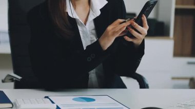 Ofiste cep telefonu ve laptop kullanan bir iş kadını.