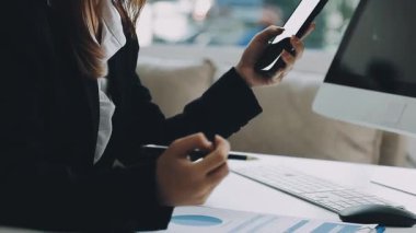 Genç iş kadını akıllı telefon kullanıyor ve ofiste notlar alıyor, modern ofiste çalışıyor.