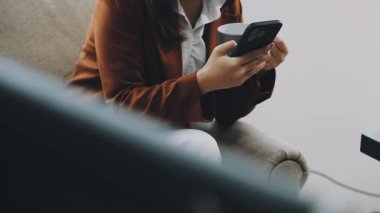 Evde akıllı telefon kullanan genç bir kadın..