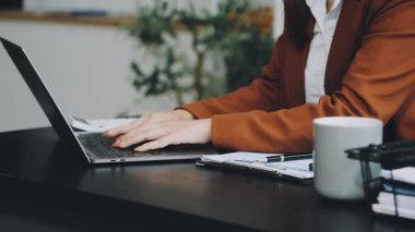 Evde dizüstü bilgisayar ve akıllı telefonla çalışan bir kadın.