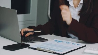 Bilgisayarı ve hesap makinesiyle ofiste genç bir kadın var..