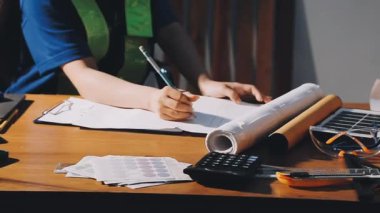 Ofiste çalışan genç kadın mühendis, hesap makinesi ve çizim yapıyor.