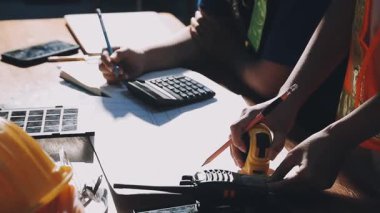 Ofisteki evi hesaplamak için hesap makinesi kullanan inşaat işçisi.