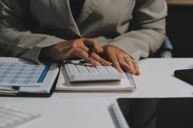 Asyalı iş kadını dizüstü bilgisayar kullanıyor ve ofiste hesap makinesi ile çalışıyor, mali raporu, iş planı yatırımını, mali analiz konseptini analiz etmeyi planlıyor..