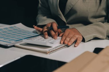 Asyalı iş kadını dizüstü bilgisayar kullanıyor ve ofiste hesap makinesi ile çalışıyor, mali raporu, iş planı yatırımını, mali analiz konseptini analiz etmeyi planlıyor..