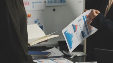 Takım elbiseli genç işadamı ofiste çalışıyor, akıllı telefondan konuşuyor.