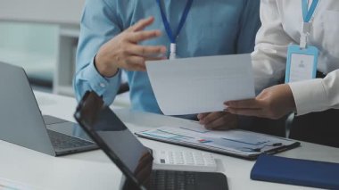 Takım elbiseli işadamı laptopla ve ofiste belgelerle çalışıyor.