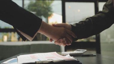 Modern bir ofiste başarılı bir anlaşmadan sonra iş adamı el sıkışıyor..