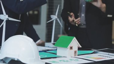 Ofiste çalışan iş adamları ve masanın üzerinde planlar var.