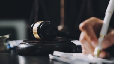 Yargıç tokmağını ve kitabını masaya koy.