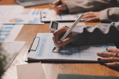 Group of confident business people point to graphs and charts to analyze market data, balance sheet, account, net profit to plan new sales strategies to increase production capacity.