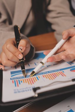 Group of confident business people point to graphs and charts to analyze market data, balance sheet, account, net profit to plan new sales strategies to increase production capacity.